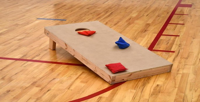 wooden cornhole board with a hole to toss the beanbag in to
