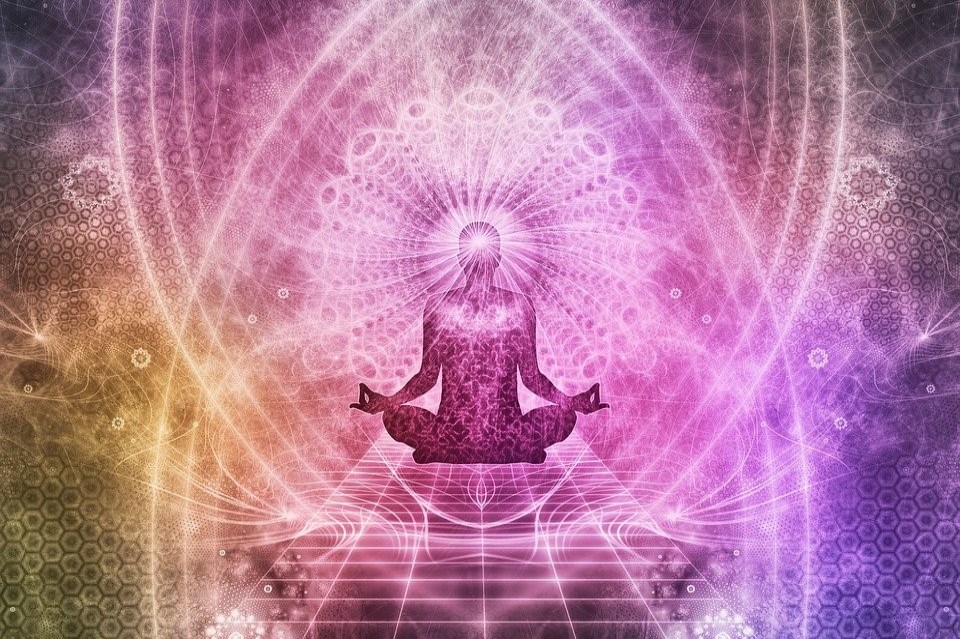 silhouette of a woman meditating in front of an aura background