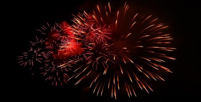 black night sky covered in bursts of red fireworks