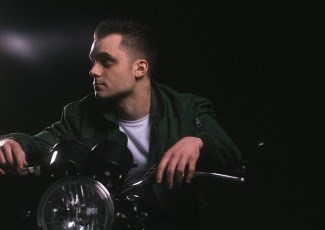 Singer Riley Michaels sitting on a motorcycle wearing a leather jacket