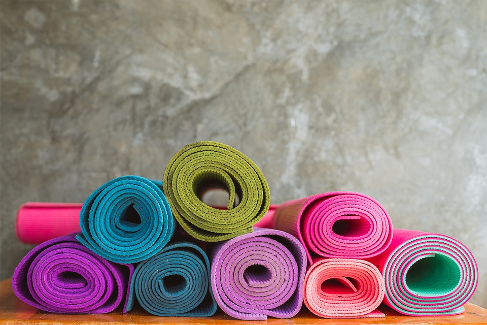 many colourful yoga mats rolled up and stacked on top of each other