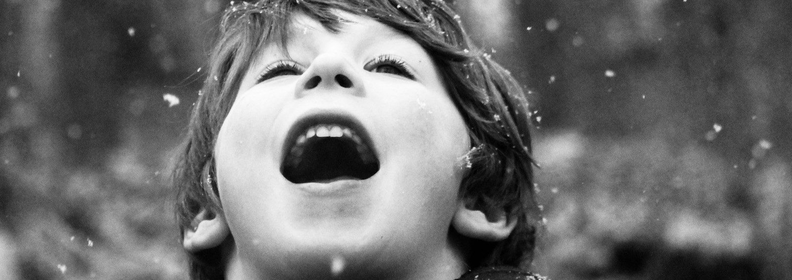 Photo of child catching snowflakes in his mouth