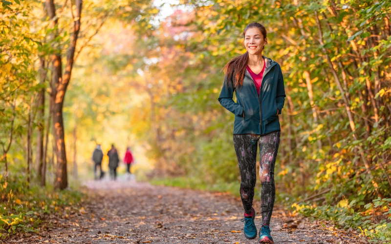 Woman walking down trail surrounded by trees