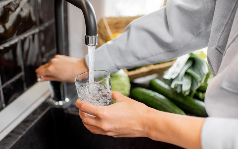 Person filling glass with water from sink tap