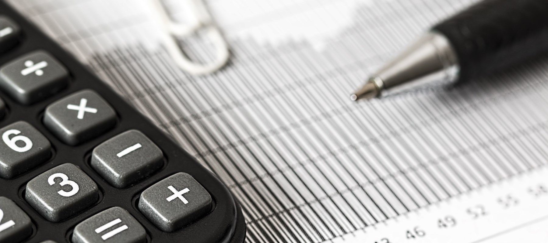 Calculator, paperclip and pen on top of report
