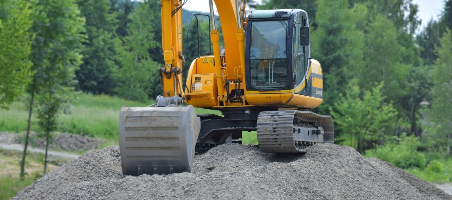 yellow excavator on pile of dirt