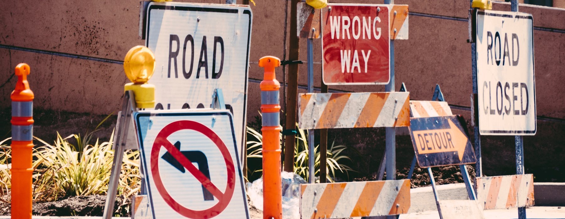 Variety of construction and road signs on sidewalk