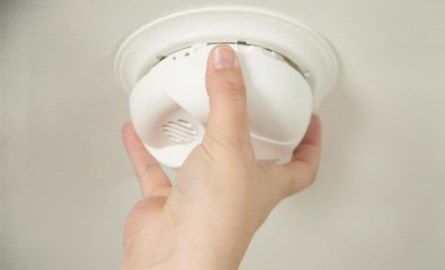 person installing smoke alarm in ceiling